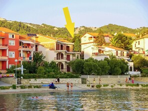 Un hôtel situé au bord de l’eau, doté de balcons, d’un mur en pierre et offrant une vue sur le plan d’eau.