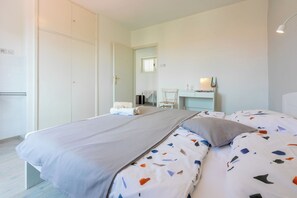 Ein Schlafzimmer mit einem Bett, einem Schreibtisch, einem Stuhl und einem Kleiderschrank.