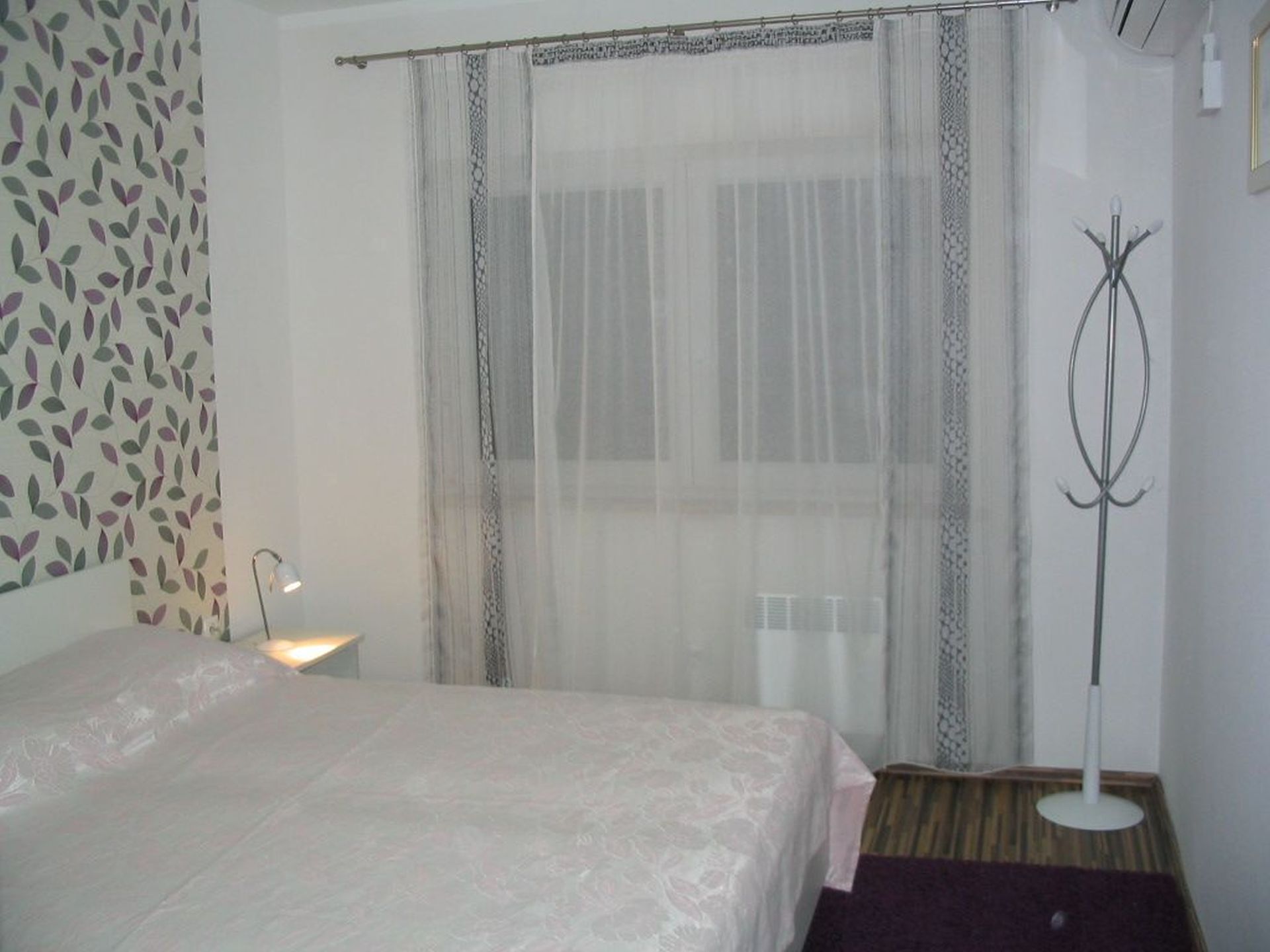 A hotel room with a bed, a standing lamp, and a floor lamp.
