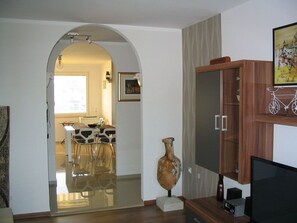 A modern living room with a wooden cabinet, a television, and a decorative vase.