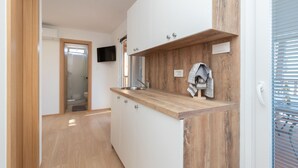 Une cuisine moderne avec des plans de travail en bois, des armoires blanches et un téléviseur encastré.