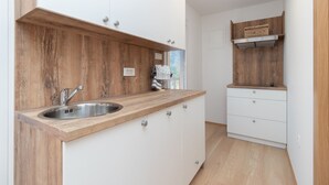 Une cuisine moderne dotée d’un plan de travail en bois, d’un évier en acier inoxydable et de meubles blancs.