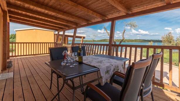 Une terrasse en bois avec une table dressée pour le repas, donnant sur un lac.