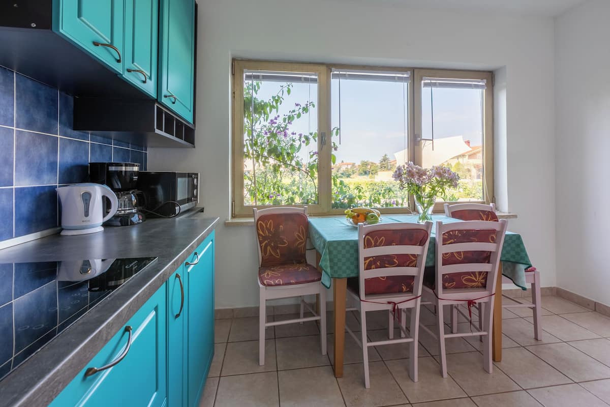 A kitchen with teal cabinets, a coffee maker, and a dining area with a table and chairs.