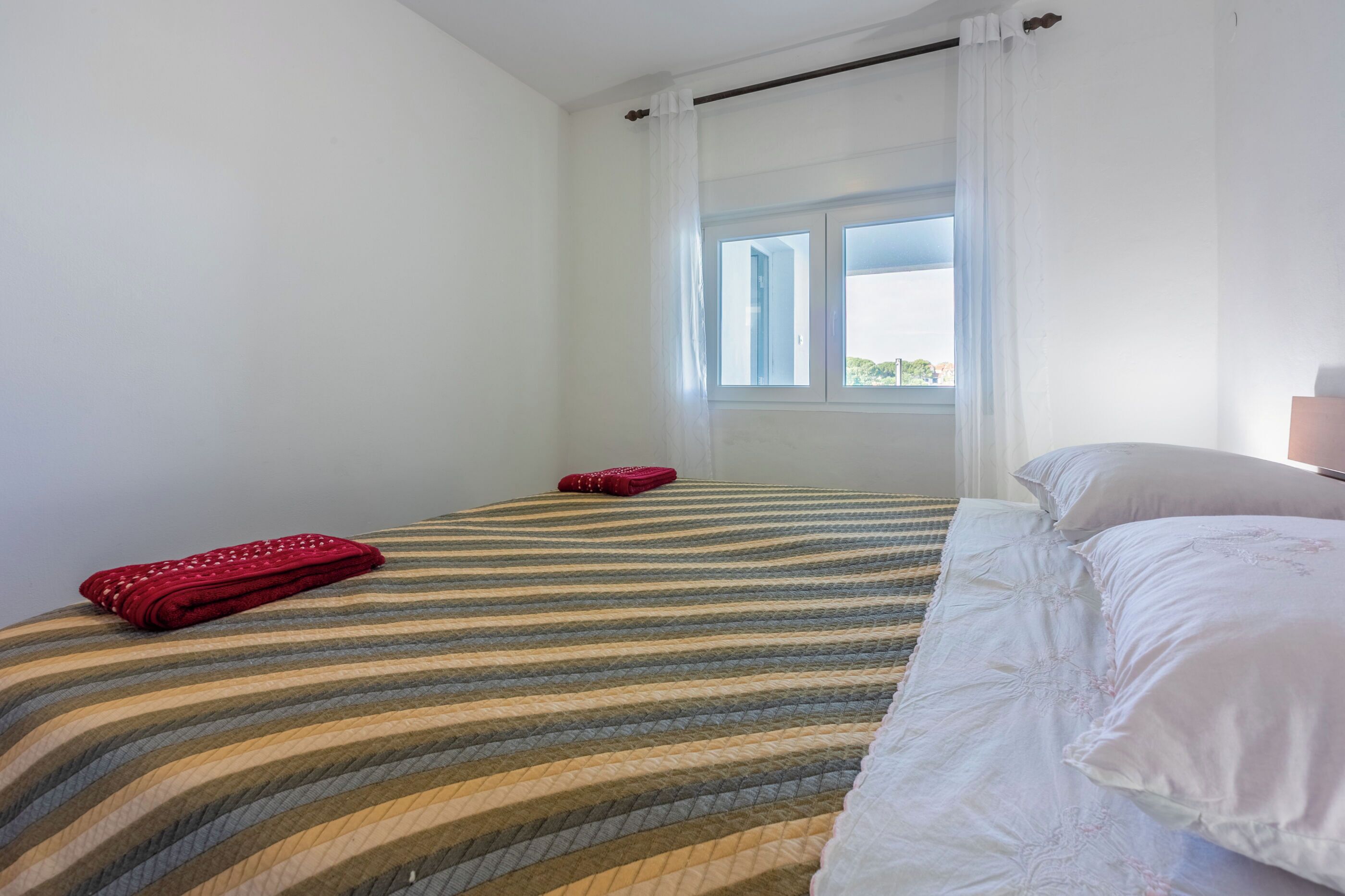 Quarto com cama, janela com cortinas e vista para o exterior.