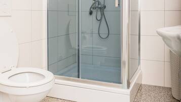 Un baño moderno con ducha de mampara de vidrio, inodoro blanco y lavabo.