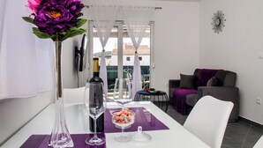 A modern living room with a dining table, a vase with flowers, a wine bottle, and a glass. - Apartments Zdeslav (Rogoznica)