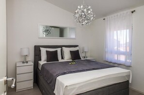 Ein Schlafzimmer mit einem Bett, Nachttischen, einem Spiegel und einer Chandelier.