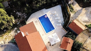 Vista aérea de una propiedad con piscina, sillas de descanso y zona de patio.