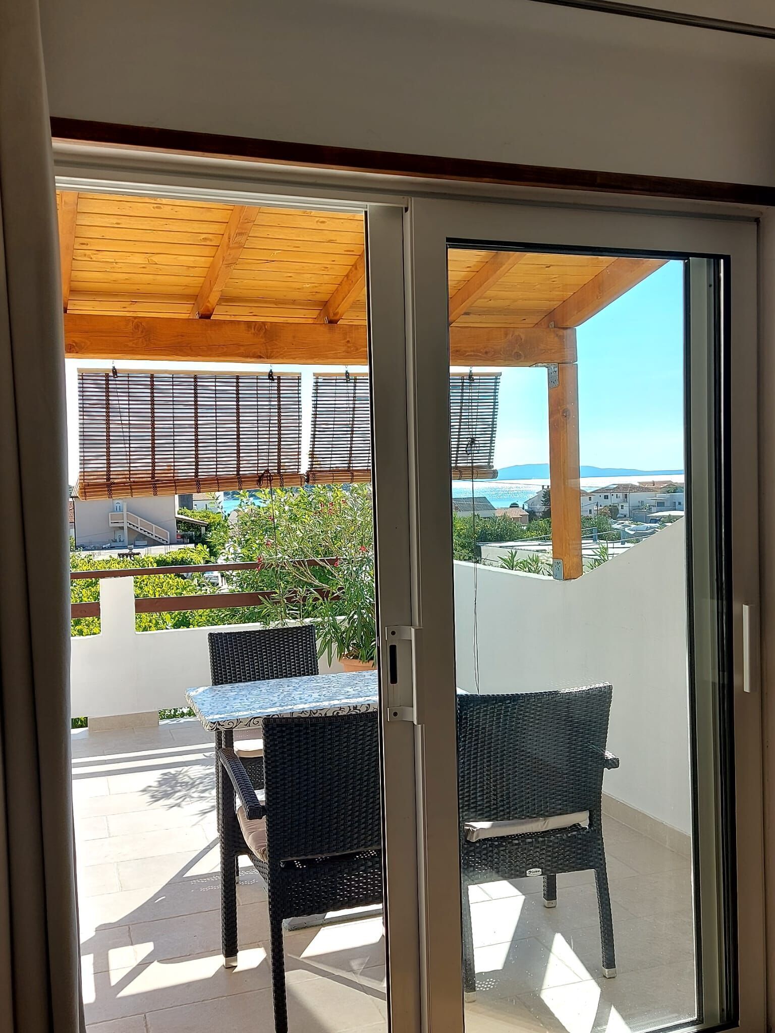 A balcony with a wooden ceiling, a table, and two chairs.
