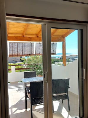 A balcony with a wooden ceiling, a table, and two chairs. - Apartments Slavica (Banjol)