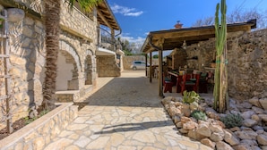 A stone pathway leading to a rustic building with a balcony and outdoor seating area. - Villa Romantic (Bribir)