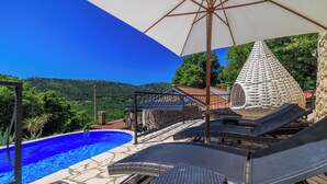 A poolside area with lounge chairs, a pergola, and a view of a mountain. - Villa Romantic (Bribir)