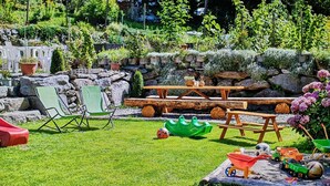 Un jardin équipé d’une table de pique-nique, de chaises et d’un espace de jeux avec des jouets.