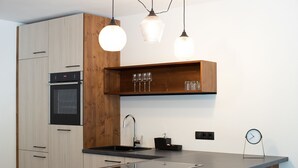 Une cuisine moderne avec des meubles en bois, un four encastré, un évier et des luminaires suspendus.