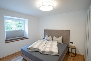 Une chambre à coucher avec un lit, une fenêtre, une table de chevet et un luminaire au plafond.