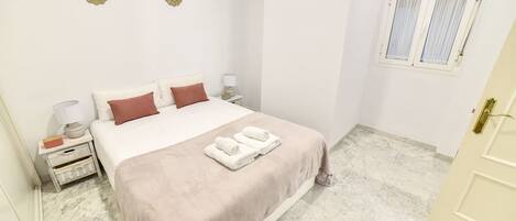A neatly arranged bedroom with a bed, bedside tables, a window, and a door.