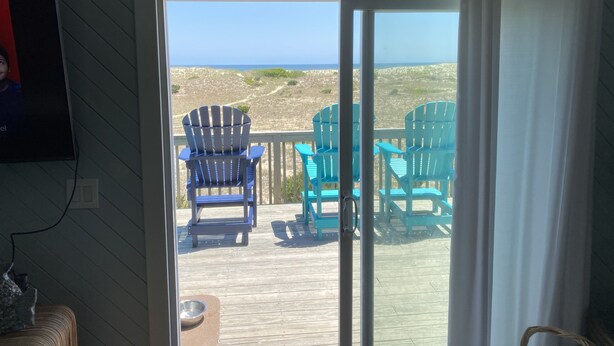 A room with a sliding glass door leading to a deck with chairs and a view of the beach. - OCEANFRONT- Hatteras Island/Salvo: 2 Primaries, Hot Tub, Large Open Living Space (Salvo)