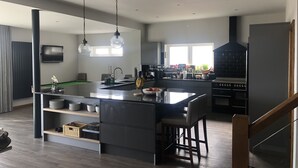 Una cocina moderna con una isla grande, electrodomésticos integrados y un comedor.