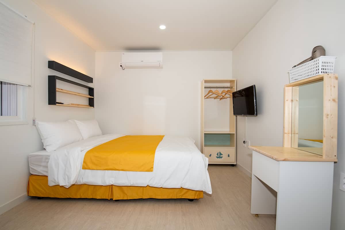 A bedroom with a bed, a TV, a mirror, and a wardrobe.