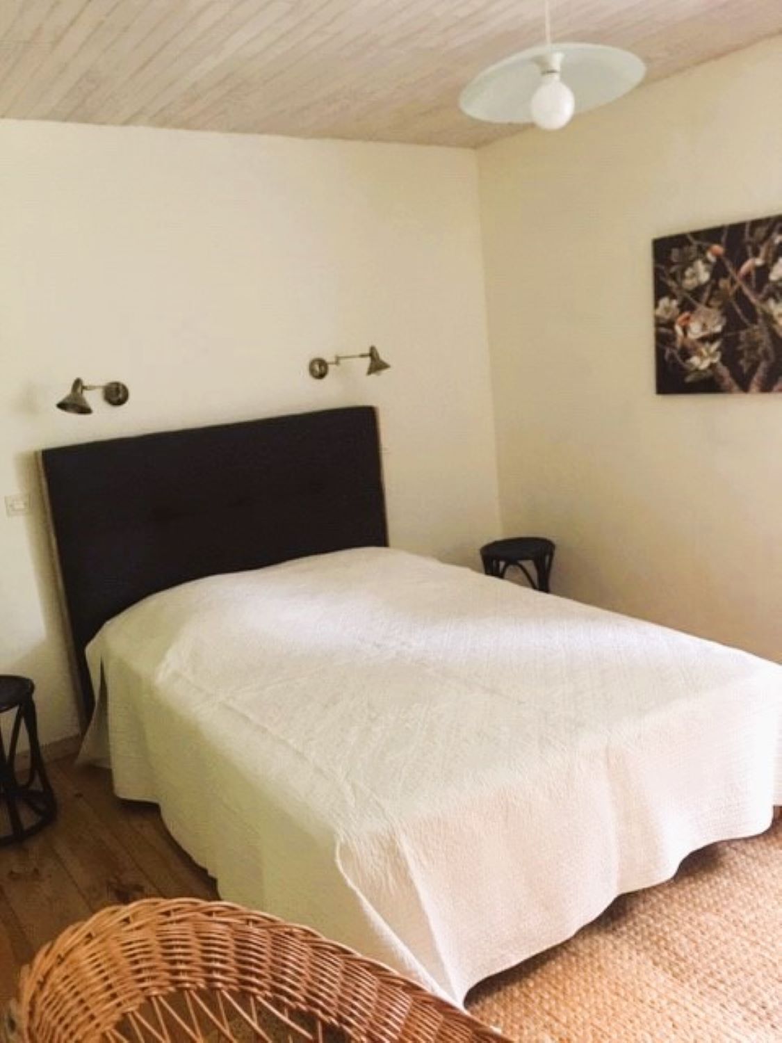 Une chambre à coucher avec un lit, une chaise, une petite table et un ventilateur de plafond.