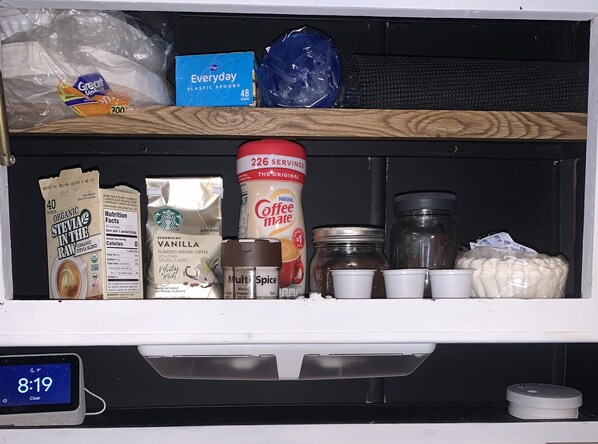 Un réfrigérateur contenant divers aliments et boissons, notamment un carton de Nestlé Coffee Mate, un paquet de café moulu aromatisé à la vanille de Starbucks et un récipient de stévia biologique non raffinée.