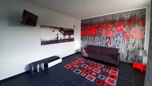A modern living room with a black and white abstract painting, a red sofa, and a patterned rug. - Casa Appartamento Vacanza La Rondulina Suite (Tigliole)