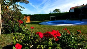 A garden with red flowers, a small orange structure, and a circular pool area. - Casa Appartamento Vacanza La Rondulina Suite (Tigliole)