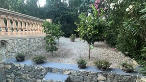 Un escalier en pierre mène à un espace jardin agrémenté de plantes en pot et d’un mur décoratif.