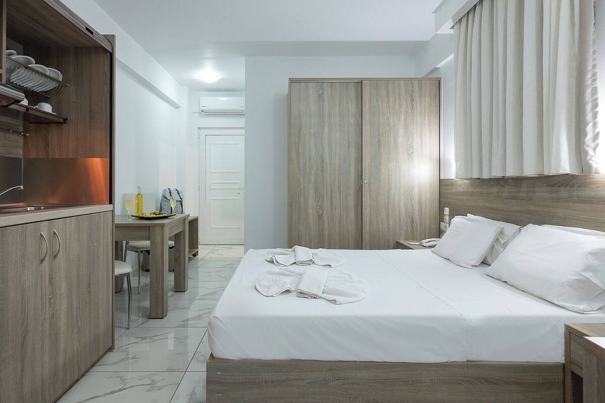 Habitación de hotel con cama, armario de madera y un escritorio pequeño con silla.