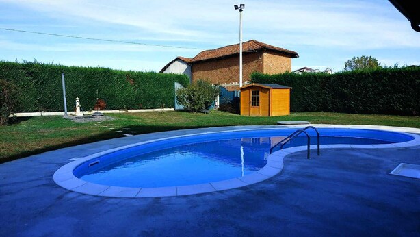 A swimming pool with a small wooden structure nearby, surrounded by a well-maintained lawn and a house in the background. - La Rondulina Classica (Tigliole)