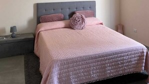 A bedroom with a bed, a nightstand, a lamp, and a wall-mounted light fixture. - La Rondulina Classica (Tigliole)