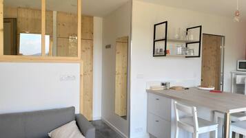 Een moderne keuken met witte kasten, een houten accentmuur en een inbouweiland met barkrukken.