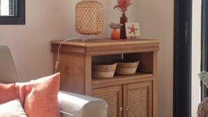 A room with a wooden cabinet, a wall-mounted hat rack, a lamp, and a small decorative item. - La Plage à Pied ! (Trégunc)