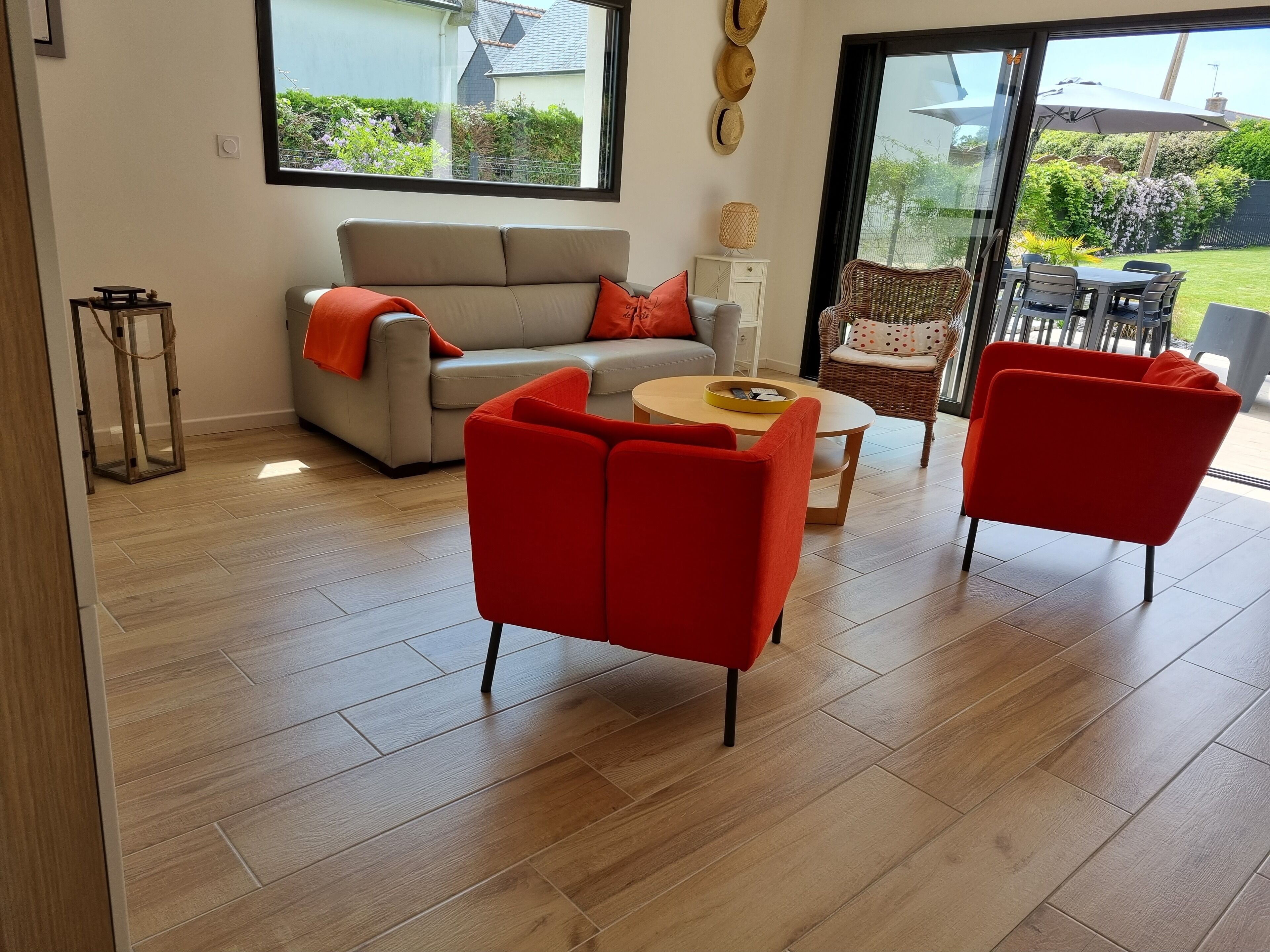Un salon moderne comprenant un canapé, deux fauteuils rouges, une table basse et un coin repas avec une table et des chaises.