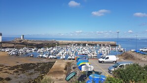 A marina with numerous boats docked, a lighthouse in the background, and a rocky shoreline. - La Plage à Pied ! (Trégunc)