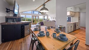 Een moderne keuken met een eethoek, grote ramen en uitzicht op de omgeving.