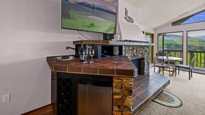 Een moderne keuken met een achterwand van steen, een inbouwvaatwasser en een flatscreen televisie boven het aanrecht.