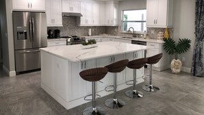 A modern kitchen with white cabinets, stainless steel appliances, and a central island with bar stools.