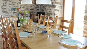 A wooden dining table set with chairs, a vase with flowers, and a bottle of wine.