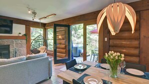 A modern interior with a dining area, wooden walls, and a fireplace. - Family Lake Access Chalet w/ Spa (Lac-Supérieur)
