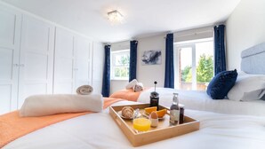A hotel room with a bed, a tray with breakfast items, a window with curtains, and a painting on the wall. - Luxury Apartment w/ Roof Terrace & Parking, Town Centre (Great Yarmouth)