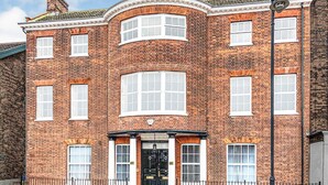 A brick building with a curved facade, large windows, and a black entrance door.