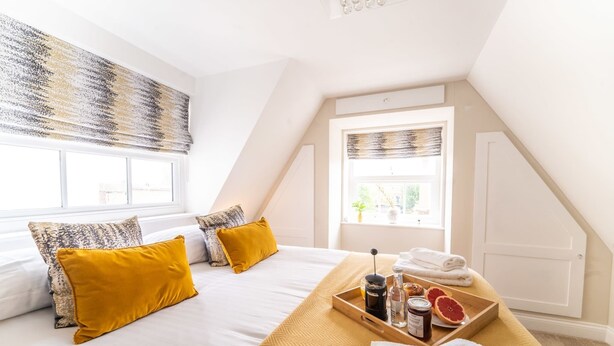 A bedroom with a bed, pillows, a tray with toiletries, and a window.