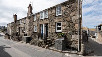 Traditional stone-built house with a central entrance and two chimneys, offering a quaint living experience.