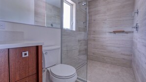 Ein modernes Badezimmer mit einer Duschkabine aus Glas, einem Holzwaschtisch und einer weißen Toilette.
