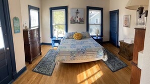 A bedroom with a large bed, a dresser, a nightstand, and a lamp. - Great place for a large family reunion! (New London)