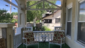 A covered patio with two white chairs and a small table, surrounded by a white railing. - Great place for a large family reunion! (New London)