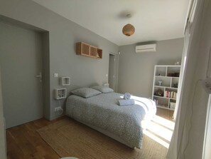 Een slaapkamer met een bed, nachtkastjes, een kledingkast en een airconditioning.