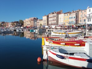 Un port de plaisance avec des bateaux amarrés, des bâtiments en arrière-plan et un ciel dégagé.